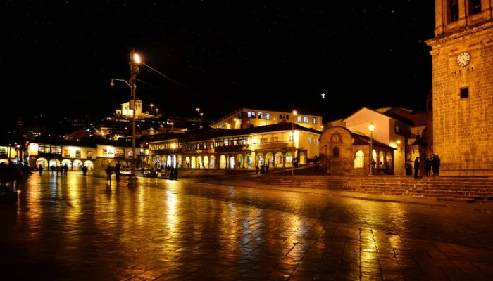 Vista nocturna de Cusco, con sus calles iluminadas y la majestuosidad de la Plaza de Armas enmarcada por la arquitectura colonial.